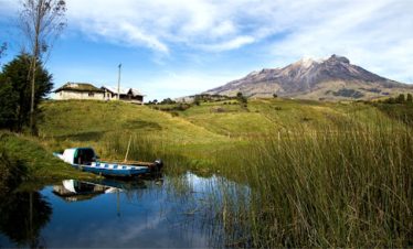 Una lancha en el muelle, rodeado de agua y con el volcan cumbal al fondo.