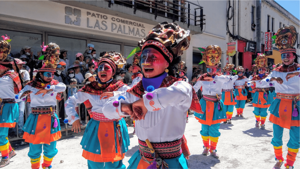Un colorido desfile del canto a la tierra del carnaval de negros y blancos de Pasto; con bailarines de los colectivos correograficos con trajes tradicionales, máscaras vibrantes y pintura facial. Actúan con alegría ante un público entusiasta.