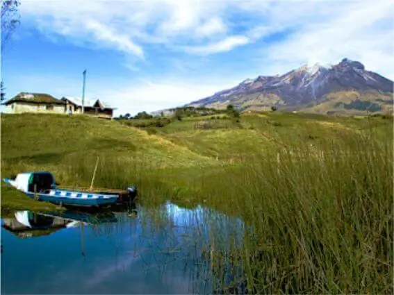 Una lancha en el muelle, rodeado de agua y con el volcan cumbal al fondo.